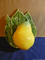 Front view of ceramic pear wall pocket mounted on leaf shaped back.