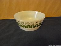 Full view of the white milk glass bowl showing the overall shape and the retro green teardrop design around the outside.