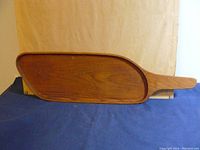 Full view of paddle-shaped teak serving tray with handle
