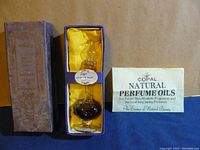 Vintage Copal natural perfume oil bottle with label 'Lily of the Valley' in original purple and yellow padded box with informational pamphlet.