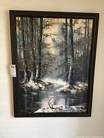 Full view of the framed winter landscape painting showing snow-covered trees and a reflective river under a cloudy sky.