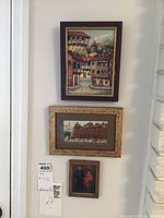 Photo of all three framed pieces hung on a white wall showing relative scale and framing styles.