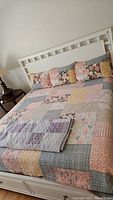 Full view of king size bed with patchwork bedspread and matching pillows.
