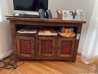 Front view of wood cabinet showing three doors along bottom and open shelf above with various items on top