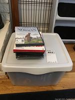 Photo of a stack of DVDs and a plastic bin containing more DVDs or media.