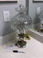 Full view of the vintage metal table lamp with ornate glass shade on a white stone base, showing overall condition and detailing.
