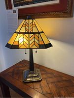 Front view of the lamp illuminated on a wooden table, showing overall shape and glow.