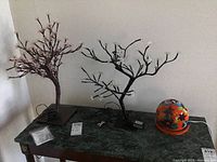 Two bonsai style lighted trees and one ceramic orange floral-lit dome on a table.