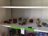 Shelf holding a variety of small animal-shaped ornaments including a cat, frog, pig, horse, starfish, and others.