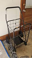 Front and side views of a metal folding shopping cart with cushioned handle and wire basket. Show wheels and folding frame.