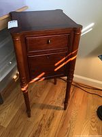Full view of the wooden side table showing drawer, door, and legs