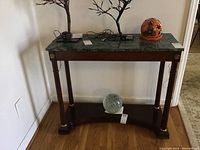 Full view of the wooden side table with green stone top against a neutral background showing table shape, legs, and stone surface.
