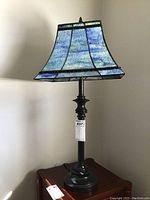 Full view of stained glass style lamp with blue-green shade and black base.