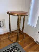 Full view of round painted rebar stand with attached top placed against wall and next to window showing the front and side profile.