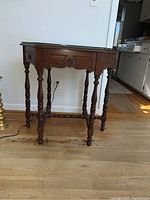 Hexagonal wooden side table with carved decorative legs and loose glass top shown fully assembled.