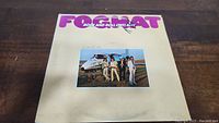 Front cover of Foghat's Rock and Roll Outlaws album showing band members and helicopter with signatures on cover.