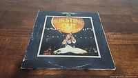 Front cover of Jethro Tull Live Bursting Out vinyl LP album featuring Ian Anderson performing on stage with 'Bursting Out' title.