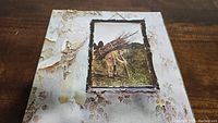 Front cover of Led Zeppelin IV album showing aged and peeling album sleeve with elderly man carrying sticks image.