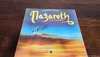 Front cover of Nazareth Greatest Hits album showing sunset sky background with yellow text and handwritten 'Hartley'