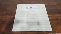 White album cover featuring a white brick wall design with handwritten 'K H' on the front cover.