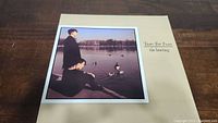 Front cover of Tears For Fears The Hurting vinyl album showing band members by a lake with ducks.