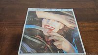Front cover of The Cars self-titled vinyl album featuring a woman smiling behind a car steering wheel.