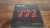 Front cover of The Police's Ghost In The Machine vinyl LP showing digitally styled red numerals and black background.
