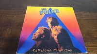 Front cover of The Police 'Zenyatta Mondatta' vinyl record album showing band members and colorful gradient background.