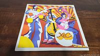 Front cover of the XTC Oranges & Lemons vinyl showing colorful artistic illustration of band members playing instruments.