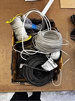 Box filled with assorted coils of long wiring in black, white, and clear/white insulation in various lengths and thicknesses.