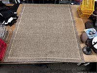 Full view of the brown rug spread out flat showing texture, border and fringing on edges.