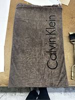 Gray Calvin Klein towel laid flat showing full logo and texture.