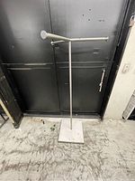 Full view of the three armed clothing rack showing the entire structure including the metal arms and heavy square base.