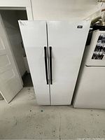 Front view of large white double door refrigerator with black handles.