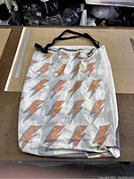 Large satchel bag lying flat on table showing orange and blue lightning bolt pattern on beige fabric