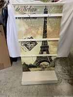 Front view of rolling display rack featuring graphic of Eiffel Tower, three horizontal bars.