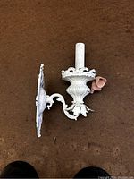 Side view of vintage white ornate metal wall sconce with pink porcelain flower and faux candle light