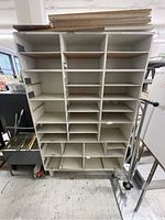 Front view of large white cubby shelf with multiple compartments and some removable shelves on top.