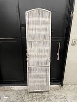 Front view of the tall wicker dividing wall panel with arched top and visible wear.