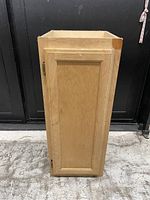 Photo of the front side of the wooden cabinet showing the closed door and wood wear