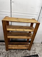 Front view of wooden shelving unit showing four slatted shelves and overall structure.