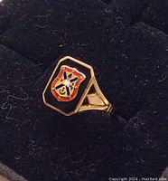 Close-up angle of the vintage gold ring showing the Queen's University enamel crest on black onyx bezel.