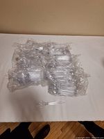 Clear plastic disposable spoons arranged in multiple sealed bundles on a table with one spoon placed separately in front.