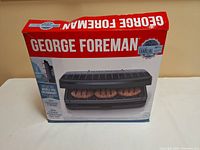 Box of George Foreman Family Size electric grill showing branding and imagery of grill with burgers cooking