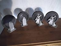 All four wheels displayed showing two locking wheels and two non-locking wheels on a wooden surface.