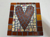 Full frontal photo showing the entire mosaic artwork with heart motif and surrounding floral patterned crockery pieces.