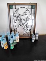 Frontal photo of framed stained glass heron picture with paint bottles in front