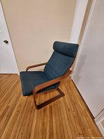 Side angled view of the chair showing the wooden frame and blue cushioned seat and headrest detail.