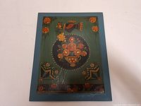 Full front view of the vintage tole painting showing overall composition with bird above floral basket on green background framed in blue.