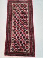 Full view of the rectangular wool rug with geometric floral pattern in dark red, cream, and brown hues with multiple intricate borders.